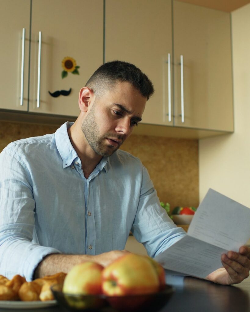 Man leest fronsend een brief aan de keukentafel